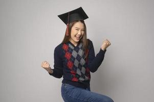 ung leende kvinna innehav gradering hatt, utbildning och universitet begrepp foto