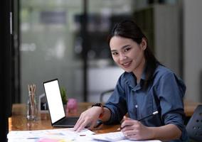 skott av en asiatisk ung företag kvinna arbetssätt på bärbar dator dator i henne arbetsstation.porträtt av företag människor anställd frilans uppkopplad marknadsföring e-handel telemarketing begrepp. foto