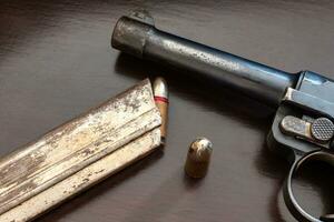 närbild av pistol och kulor på tabell. vapen och ammunition. foto
