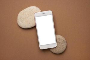 mobil telefon med vit skärm och sten på en ljus brun bakgrund. trend, minimal begrepp med copy foto