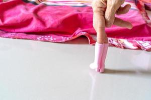 de gammal kvinnas hand spelar rosa plast stövlar leksak och posta den tycka om en modellens posta. foto