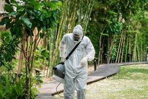 professionell specialist gående och observerar runt om de utomhus- trädgård till förbereda besprutning desinfektionsmedel flytande lösning för döda coronavirus covid 19. foto