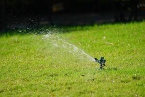 sprinkler gräs arbetssystem, arbetar på fältet i trädgården. foto