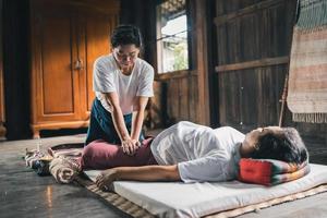 massage och spa avkopplande behandling av kontor syndrom traditionell thai massage stil. asain senior kvinna massös håller på med massage behandla hand, tillbaka smärta, ärm smärta, fot och påfrestning för gammal kvinna trött. foto