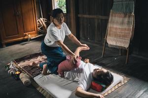 massage och spa avkopplande behandling av kontor syndrom traditionell thai massage stil. asain senior kvinna massös håller på med massage behandla hand, tillbaka smärta, ärm smärta, fot och påfrestning för gammal kvinna trött. foto