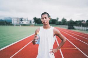 attraktiv asiatisk sport man löpare trött och törstig efter löpning träna dricka vatten. sport man begrepp foto