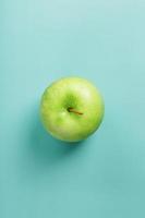ett grön äpple på en grön bakgrund med en minimalistisk sammansättning. foto