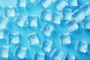 massor av is kuber med vatten droppar spridd på en blå bakgrund foto