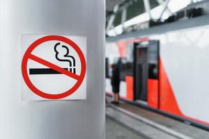 en tecken förbjuder rökning på en Pol nära de järnväg plattform. foto