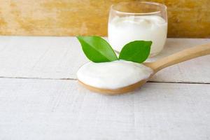 yoghurt kopp och sked på vit trä bakgrund. foto