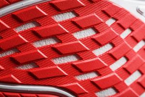löpning skor med röd sulor på en svart bakgrund. foto