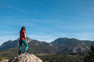 en ung kvinna klättrade till de topp av de berg och utseende på de dal foto