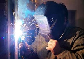 arbetare med skyddande masksvetsning av metall foto