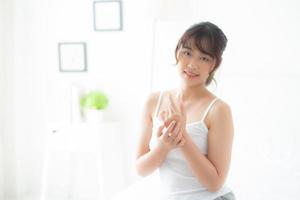 ung asiatisk kvinna som applicerar kräm och behandling för hudvård touch till hands, Asien flicka med lotion spa och återfuktande för hälsa och välbefinnande kroppsdel, livsstil och skönhet kosmetiska koncept. foto