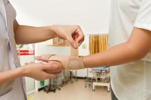 fysioterapeut hjälper kvinnans patient att bära en handledsstag foto
