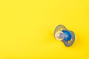 blå bebis silikon napp, på en gul bakgrund. kopia Plats. foto