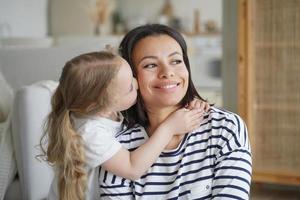 porträtt av familj, unge kramar och kyssar mamma. mor är leende. begrepp av tillgivenhet och moderskap. foto