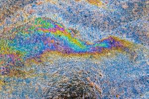 färgrik bränsle och olja på ett asfalt textur som visar enviromental förorening foto
