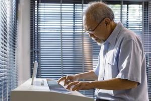 senior asiatisk konstnär man spelar och komponera musik med hans piano ensam i hans pensionering pension Hem för äldre och musiker begrepp foto