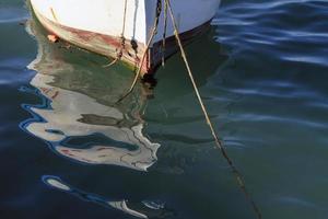 fiskebåtar som gungar fram och tillbaka i tidvattnet, med solljus som reflekteras från vattnet foto