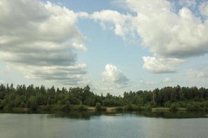 sommarlandskap med en vacker sjö med granar mot en molnig himmel foto