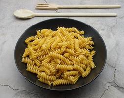 rå italiensk fusilli pasta i en svart maträtt. traditionell italiensk kök. foto