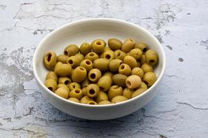 pitted grön oliver i en vit keramisk skål foto