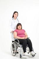 skön kvinna läkare bota krämpor av fet kvinnor patienter asiater sittande på en rullstol. fetma är en hälsa problem för de kropp. begrepp av förlorande vikt. kopia Plats. vit bakgrund foto