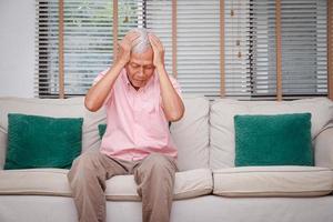 asiatisk äldre män ha huvudvärk ackumulerade påfrestning på grund av till varelse inomhus under de coronavirus 2019. begrepp av fysisk och mental hälsa problem av de äldre i pensionering ålder foto