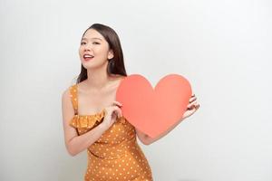 kärlek och valentines dag. sexig kvinna i polka punkt klänning innehav hjärta leende söt och förtjusande foto