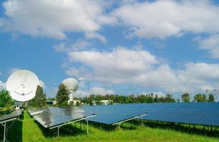 sol- bruka och grön fält med blå himmel. stor satellit maträtt nära sol- odla. sol- kraft för grön energi. solceller kraft växter generera sol- energi. förnybar energi. Sol kraft för kommersiell. foto