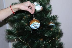 en kvinna hand dekorerar de jul träd med jul och ny år leksaker. kvinnors hand dekorerar de jul träd med girlanger. foto