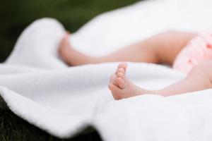 närbild av nyfödd baby flicka fötter på vit filt utomhus. moderskap och barndom koncept foto