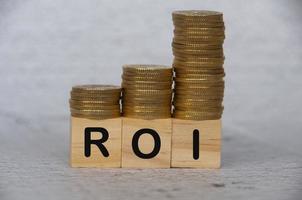 mynt stack på trä- block med roi text - företag och investering begrepp foto