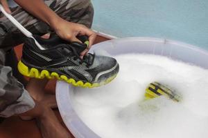 tvättning de smutsig skor eller gymnastikskor i bubbla fylld handfat. foto