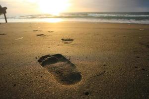 mänsklig fotavtryck på sand sommar tropisk strand på soluppgång bakgrund med copyspace. foto