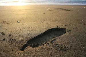 mänsklig fotavtryck på sand sommar tropisk strand på soluppgång bakgrund med copyspace. foto