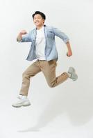 energisk Lycklig ung asiatisk man i tillfällig kläder Hoppar, studio skott isolerat foto