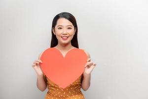 attraktiv ung asiatisk kvinna som visar röd hjärta på vit bakgrund foto
