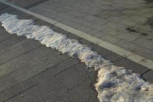 snö är smältande på väg. is på yta av tratoir. foto