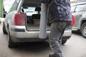 man sätter gas cylinder i trunk av bil. farlig frakt i transport. foto
