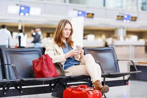 kvinna på internationell flygplats som väntar på flyg vid terminalen foto