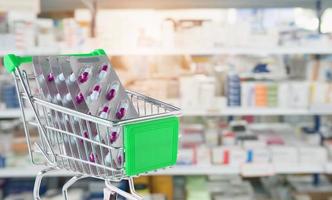 medicinska piller kapsel i kundvagn med apotek apotek hyllor suddig bakgrund foto