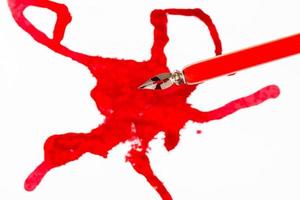 topp se av röd dopp penna över bläck färga på vit foto