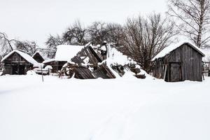 snötäckt gammal övergiven gård i by foto