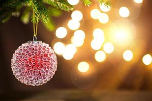 röd med is finnar jul boll på en leva gren av en gran träd med gyllene lampor av kransar i oskärpa. ny år, jul, Semester bakgrund, bokeh, kopia Plats foto