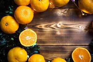 nyårshelgdagbakgrund gjord av trä med mandariner, kranslampor och grönt glitter. hälften av en apelsin, citrus arom av semestern. jul, nyår. utrymme för text. ram foto