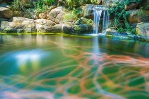 japansk trädgård vattenfall. frodig grön tropisk koi damm med vattenfall från varje sida. en frodig grön trädgård med vattenfall cascading ner de klippig stenar. zen och fredlig bakgrund. foto