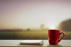 en röd kopp av kaffe och notera vaddera på trä- tabell och ängar på morgon- tid suddigt bakgrund foto