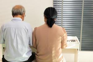 äldre senior par spela piano musik tillsammans. grupp av två asiatisk smart mogna person avgå och skaffa sig pension fond. morförälder uttrycka känsla Lycklig behandling. begrepp växa gammal tillsammans, kopia Plats foto